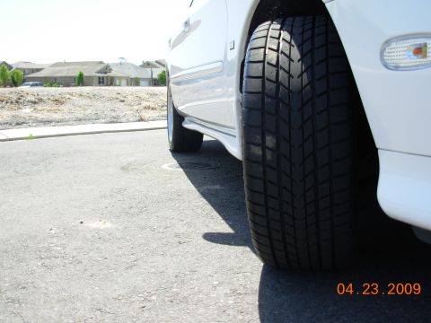 1995 Ford Taurus - Close-up of a white car's side profile, focusing on the large tire and side trim. The image is dated 04.23.2009.