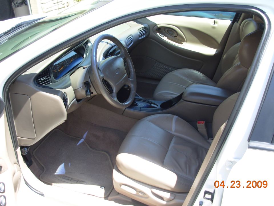 Interior shot of a white car, showing the driver's seat, dashboard, and center console