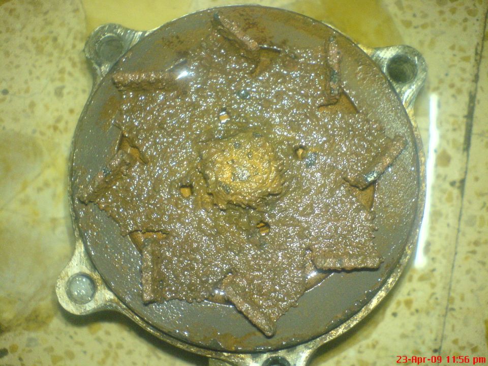 close-up of a very corroded water pump impeller with brown sludge covering the blades
