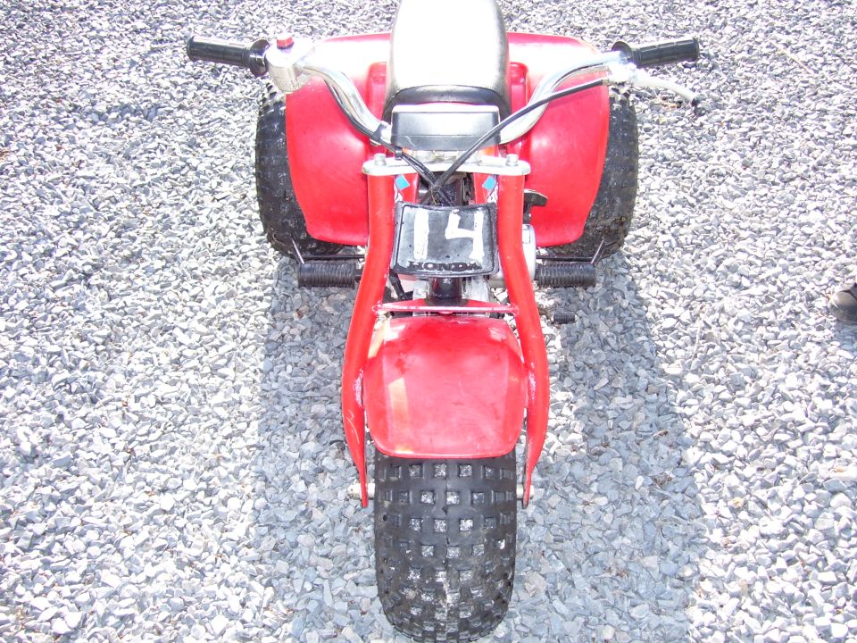 Red Honda three-wheeler ATC front view on gravel with number 14 front plate