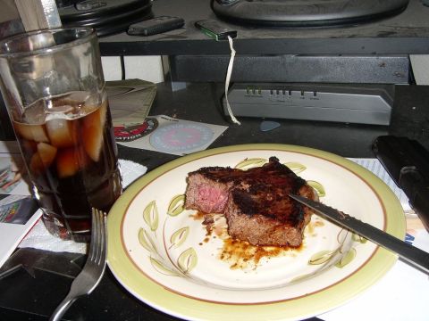 1978 Ford Bronco - A steak dinner is served on a desk next to a glass of cola.