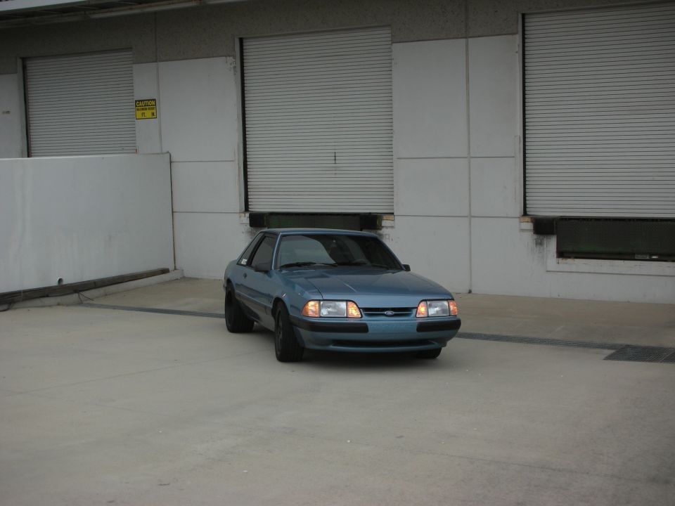 Blue coupe parked in front of industrial garage doors, front view