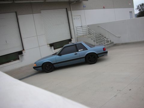 1990 Ford Mustang - Blue 1990 Ford Mustang coupe with black wheels parked near a loading dock.