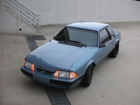 1990 Ford Mustang - A blue 1990 Ford Mustang coupe is parked outdoors on a concrete surface.