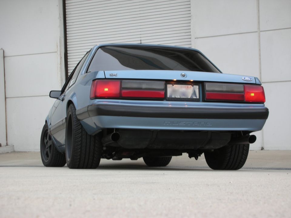 Rear view of a blue Ford Mustang parked outside a building