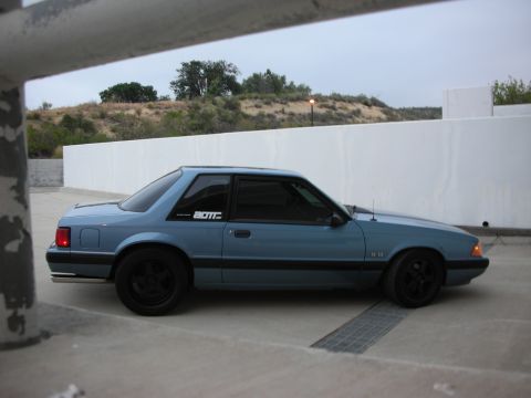 1990 Ford Mustang - A blue 1990 Ford Mustang coupe is parked outdoors, viewed from its side profile.
