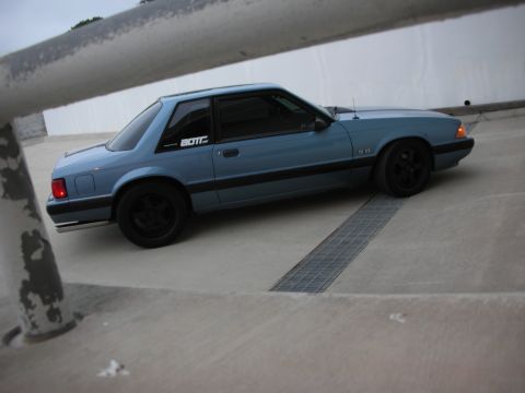 1990 Ford Mustang - This blue 1990 Ford Mustang coupe features black wheels and a "5.0" badge on the fender.