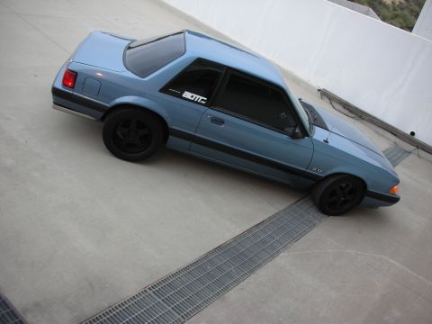 1990 Ford Mustang - A blue 1990 Ford Mustang coupe is parked on a concrete surface with metal grates.