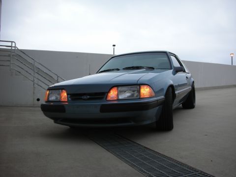 1990 Ford Mustang - This 1990 Ford Mustang is captured in a three-quarter front view, parked on a concrete surface.