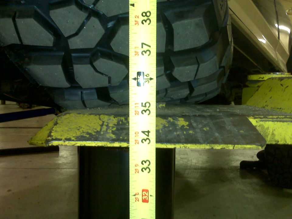 Tire on a lift with a measuring tape showing about 36 inches