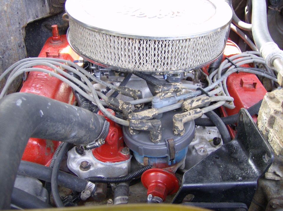 Engine bay showing air filter, distributor cap, spark plug wires, and red valve covers