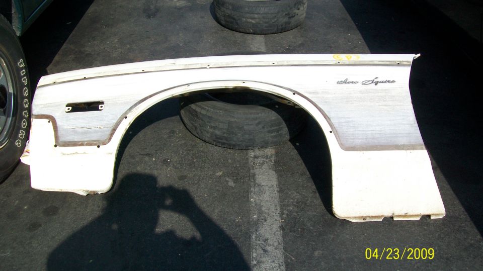 White Ford fender with "Aero Squire" script, lying on asphalt