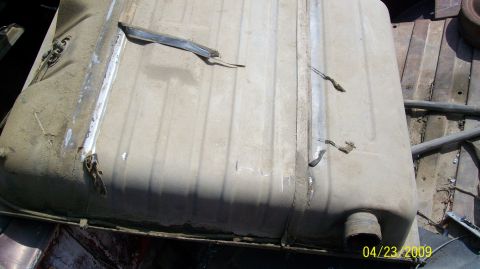 1972 Ford Ranchero - A damaged fuel tank, likely from a vehicle, sits in a yard.