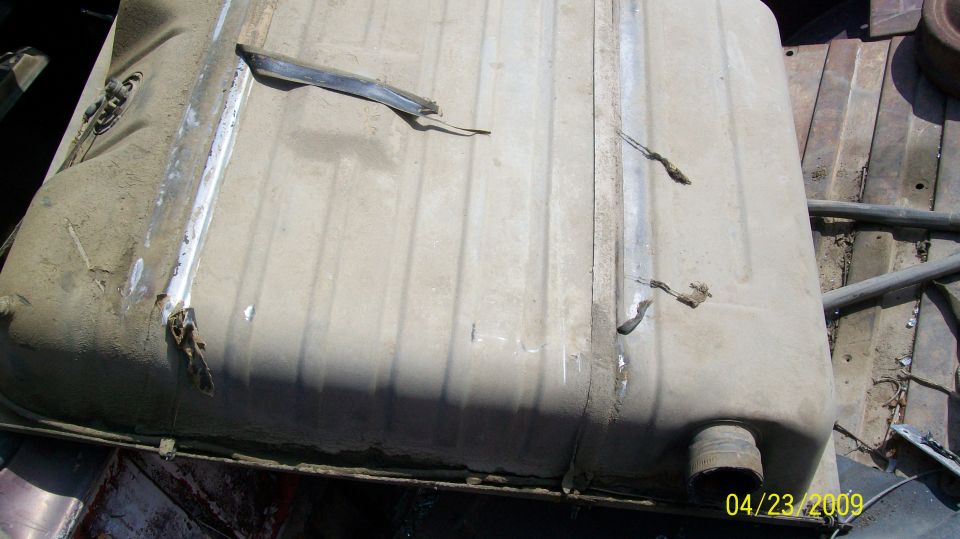 Dented, dirty fuel tank with visible rust and straps