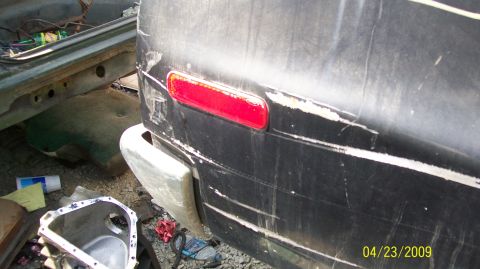 1972 Ford Ranchero - A damaged rear bumper and taillight are visible on a vehicle in a junkyard setting.