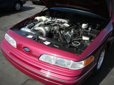 1992 Ford Crown Victoria - The engine bay of a maroon 1992 Ford Crown Victoria is displayed, a prominent turbocharger and custom modifications.