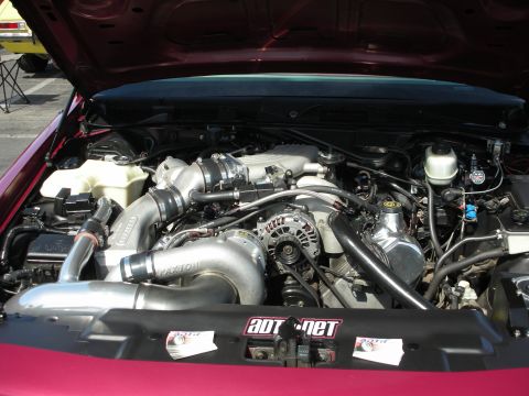 1992 Ford Crown Victoria - The engine bay of a maroon 1992 Ford Crown Victoria is visible, a supercharger and custom intake system.