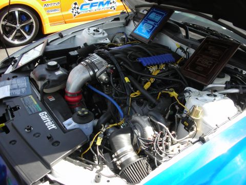 1992 Ford Crown Victoria - Engine bay a supercharger and custom parts, with another vehicle visible in the background.