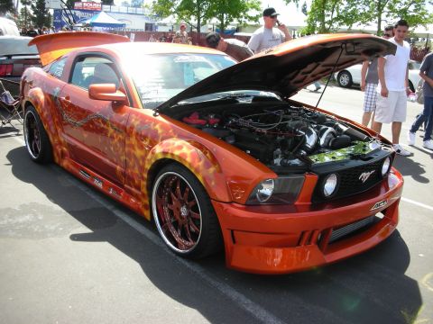 1992 Ford Crown Victoria - Customized orange Ford Mustang with flame graphics and its hood open, revealing the engine bay.