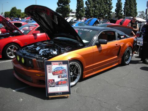 1992 Ford Crown Victoria - Orange Ford Mustang on display at a car show, with a red Mustang visible behind it.