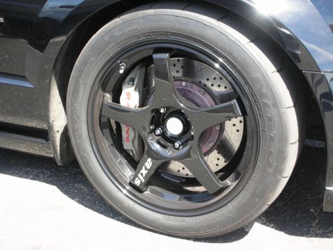1992 Ford Crown Victoria - Close-up of a black Axis wheel, drilled rotors, and performance brake calipers on a vehicle.