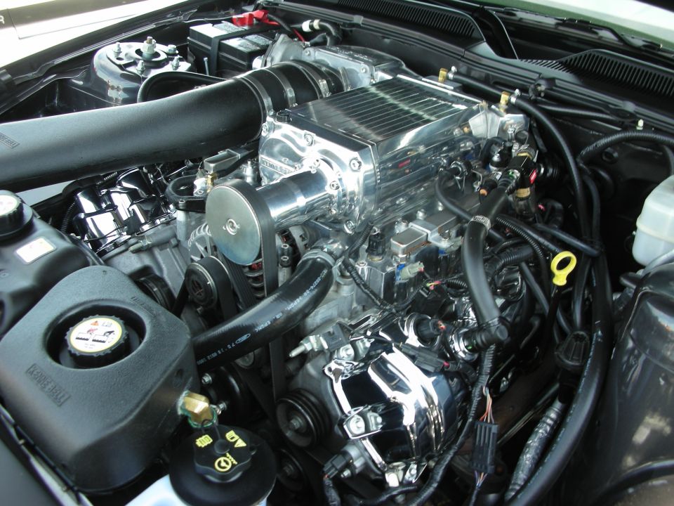Close-up of a supercharged V8 engine with chrome components and black hoses
