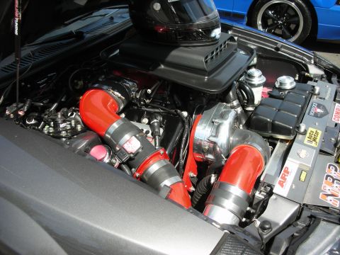1992 Ford Crown Victoria - A modified engine bay features a turbocharger and red intake piping, with a helmet resting on the air intake.