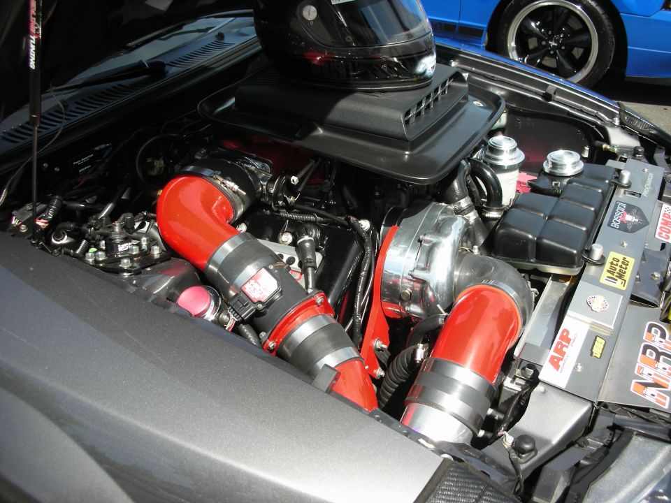 Engine bay with turbo, red intake pipes, and a helmet on the air intake