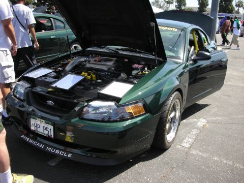 1992 Ford Crown Victoria - Green Ford Mustang with hood open, showing engine bay and "AMERICAN MUSCLE" sticker on the front bumper.