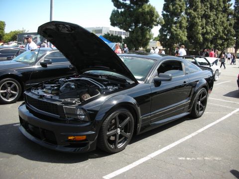 1992 Ford Crown Victoria - A black Ford Mustang is displayed with its hood open at an outdoor car show.
