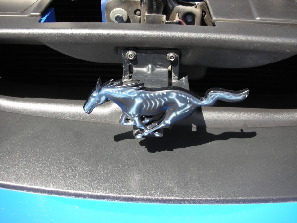 Close-up of a Ford Mustang running horse emblem on a car's grille