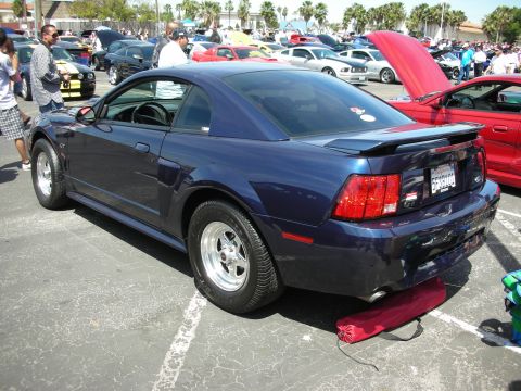 1992 Ford Crown Victoria - A dark blue Ford Mustang GT is parked at a car show with other vehicles in the background.
