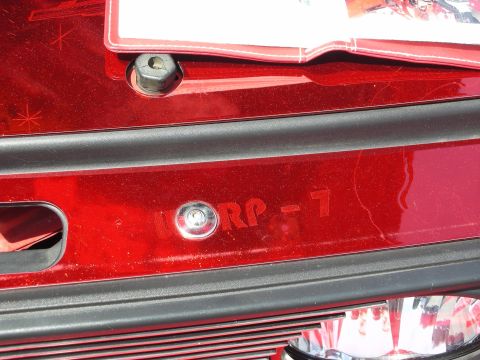 1992 Ford Crown Victoria - Close-up of a red car's rear, showing a license plate bracket and engraved text.