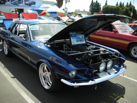 1992 Ford Crown Victoria - A blue 1967 Ford Mustang coupe is displayed with its hood open, alongside another Mustang.