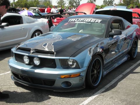 1992 Ford Crown Victoria - A modified Ford Mustang with custom paint and hood is parked at an outdoor car show.