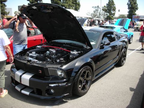 1992 Ford Crown Victoria - A black Ford Mustang is displayed with its hood open at a car show, revealing the engine bay.