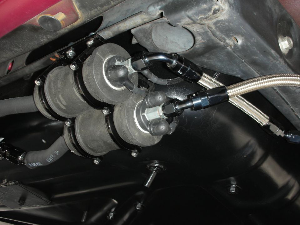 Close-up of a triple fuel pump assembly with braided lines attached to the underside of a vehicle