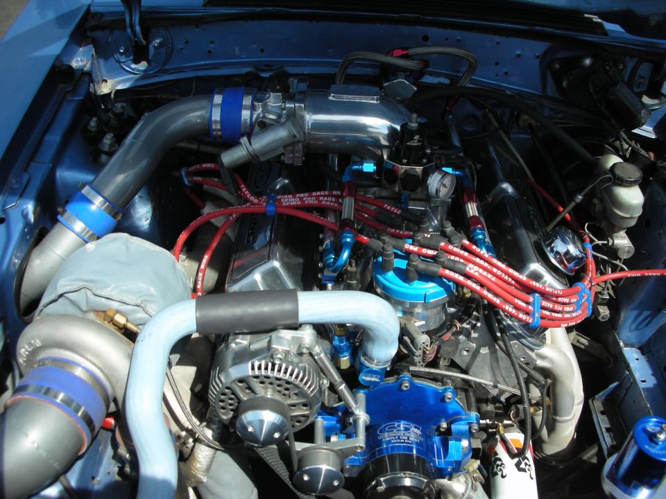 Blue engine bay with chrome intake, red spark plug wires, and a turbocharger