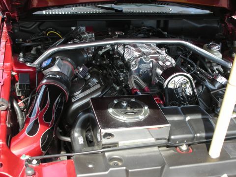 1992 Ford Crown Victoria - Close-up of a modified engine bay, a prominent chrome supercharger and custom red intake piping.