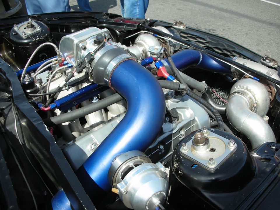 Engine bay with twin turbochargers, blue intake piping, and custom modifications