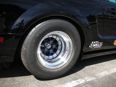 1992 Ford Crown Victoria - A close-up view of a black car's rear wheel and fender, adorned with a Weld Racing sticker.