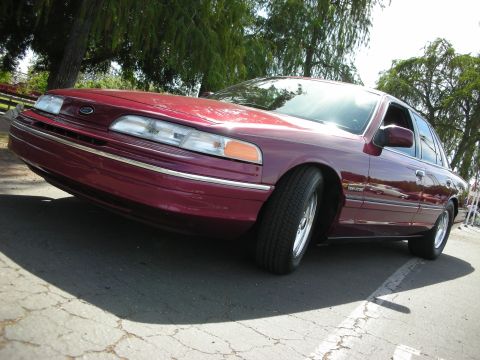 1992 Ford Crown Victoria - Maroon 1992 Ford Crown Victoria parked outdoors with trees in the background.