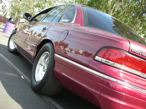 1992 Ford Crown Victoria - A maroon Ford Crown Victoria with wide rear tires is parked outdoors, showing its rear quarter panel and taillight.