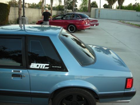 1992 Ford Crown Victoria - A blue coupe is parked next to a red convertible, with a person standing near the red car.