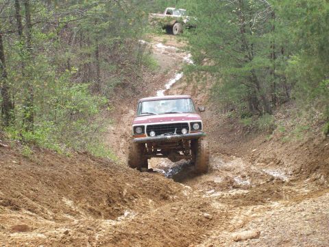 1978 Ford Bronco - 1978 Ford Bronco navigates a challenging muddy off-road course with another vehicle in the background.