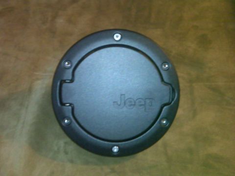 2008 Jeep Wrangler - A close-up view of a black Jeep fuel filler door, showing the brand name embossed in the center.