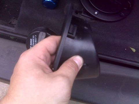 2008 Jeep Wrangler - A hand holds a black plastic component near a black cap with warning text.