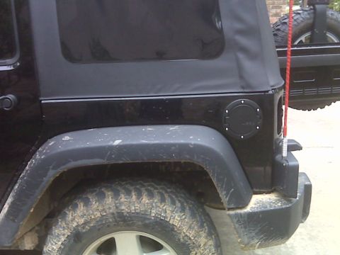 2008 Jeep Wrangler - Close-up of a black Jeep Wrangler JK showing the rear quarter panel, fuel filler, and spare tire.