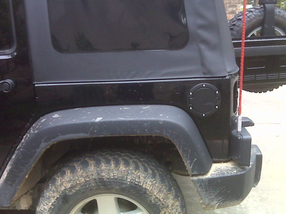 Black Jeep Wrangler JK rear quarter panel, soft top, fuel filler door, and spare tire visible
