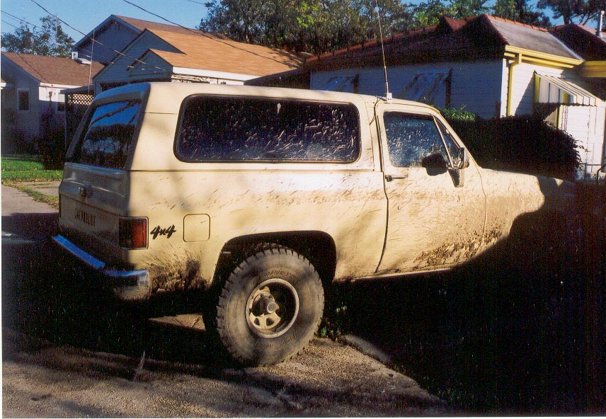 Mud-covered tan two-door Chevrolet Blazer 4x4 SUV parked in a driveway